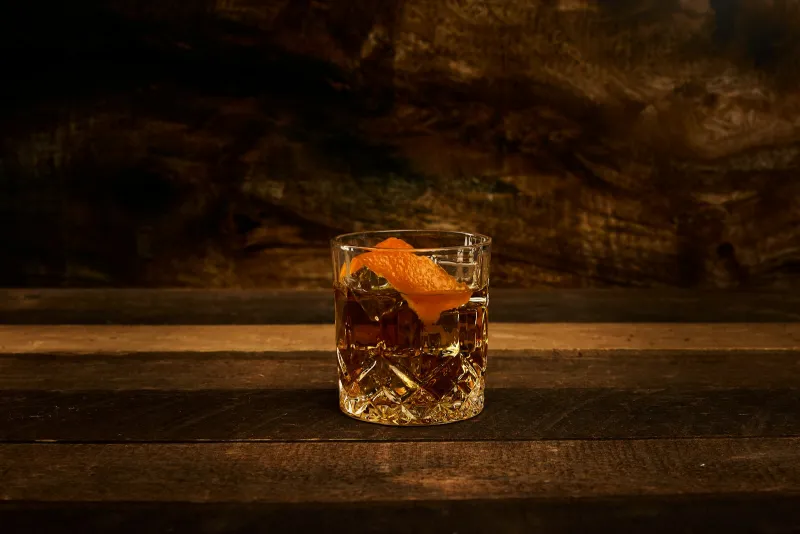 Classic Old Fashioned cocktail with orange peel over ice